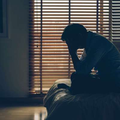 Sad businessman sitting head in hands on the bed in the dark bedroom with low light environment, dramatic concept, vintage tone color Sad businessman sitting head in hands on the bed in the dark bedroom with low light environment, dramatic concept, vintage tone color